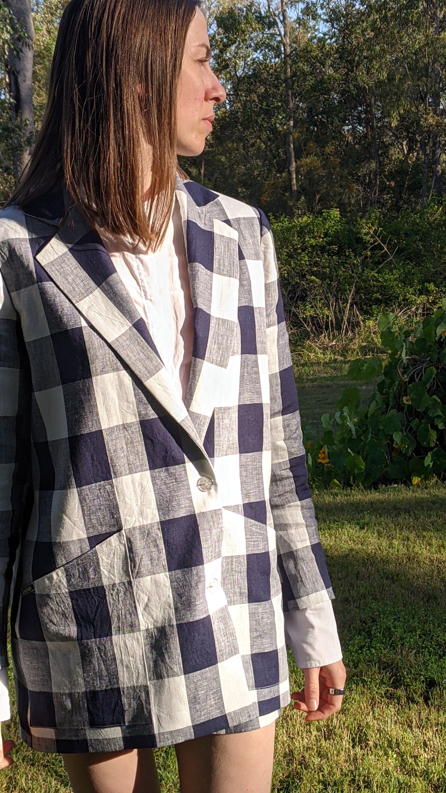 Person wearing a well tailored blue and white checked linen blazer outdoors