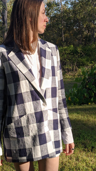 Person wearing a well tailored blue and white checked linen blazer outdoors
