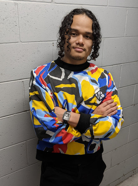 In this image Feng wears the Tidal Jumper and is looking straight at the camera. His arms are folded accross his chest so we can see his wrists and a chunky wristwatch with compliments the graphic elements of the jumper.